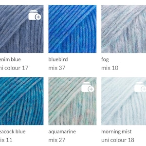 May include: A collection of six skeins of yarn in various shades of blue and teal. Each skein is labeled with a color name and a mix number. Colors include denim blue, bluebird, fog, peacock blue, aquamarine, and morning mist.