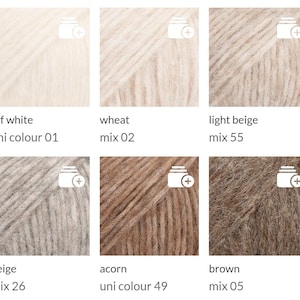 May include: A collection of six yarn skeins in various neutral colors. The colors include off-white, wheat, light beige, beige, acorn, and brown. Each skein has a label with the color name and a mix or uni colour code.