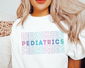 May include: White sweatshirt with the word "PEDIATRICS" repeated in a rainbow gradient pattern.