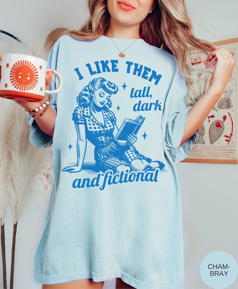 A model wears a chambray shirt that has a retro design all in medium blue that days I like them tall, dark and fictional, with a woman from the 1950s sittings and reading a book.