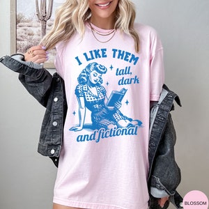 A model wears a blossom shirt that has a retro design all in medium blue that days I like them tall, dark and fictional, with a woman from the 1950s sittings and reading a book.