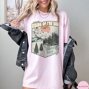 May include: An oversized pink t-shirt with a vintage graphic design featuring a mountain landscape, a bird flying, and the text "From the Rising of the Sun" and "The name of the Lord is to be praised. Psalm 113:3".
