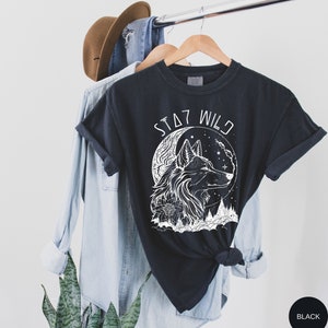 May include: Black t-shirt with a white wolf howling at the moon graphic and the text "Stay Wild".