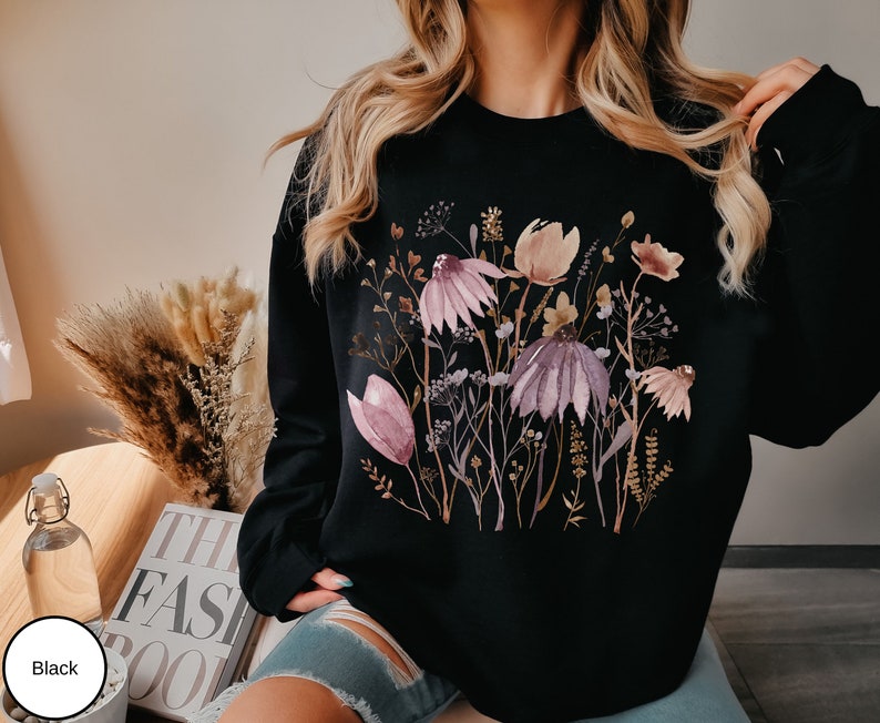 May include: Black sweatshirt with a watercolor floral print featuring pink, purple, and brown flowers on a black background.