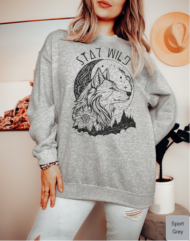May include: A gray sweatshirt with a black wolf design and the text "Stay Wild" printed on the front.
