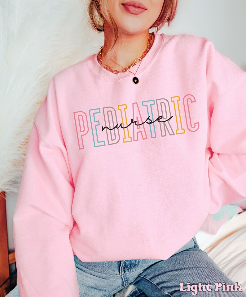 May include: A light pink sweatshirt with the text "PEDIATRIC nurse" in colorful letters.