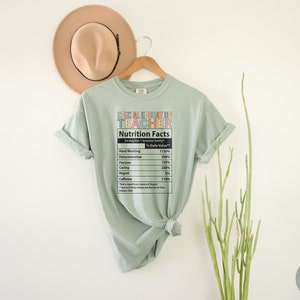 Op de afbeelding: Een lichtgroen T-shirt met een afbeelding van een voedingsschema-etiket met de tekst "Special Education Teacher". Het etiket geeft het percentage van de dagelijkse waarde voor hard werken, vastberadenheid, passie, zorg, spijt en cafe&iuml;ne.