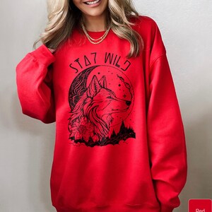 May include: Red sweatshirt with a black wolf design and the text "Stay Wild" printed on the front.