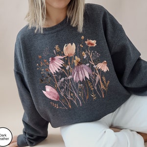 May include: A dark heather grey cropped sweatshirt with a watercolor floral print featuring pink, brown, and white flowers.