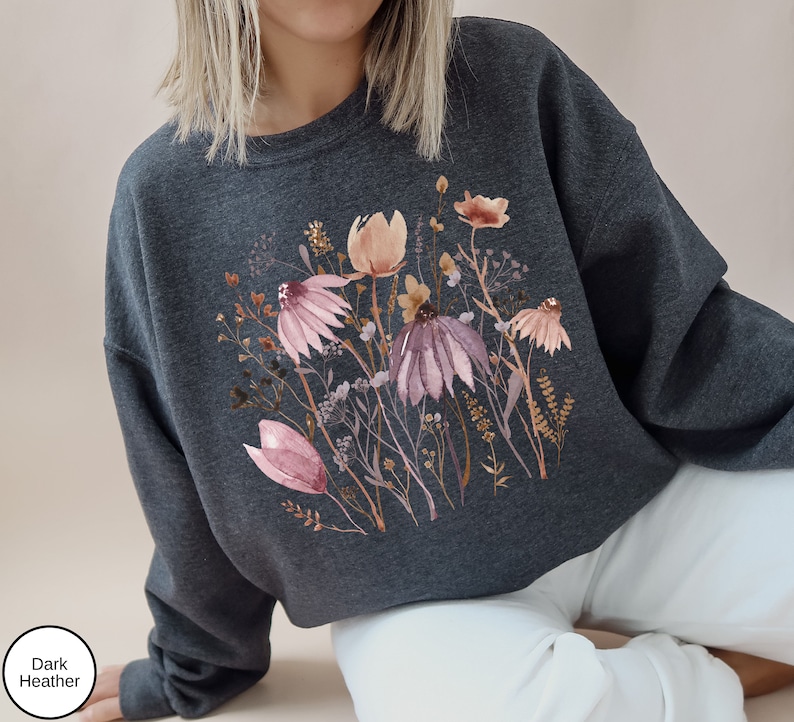 May include: A dark heather grey cropped sweatshirt with a watercolor floral print featuring pink, brown, and white flowers.