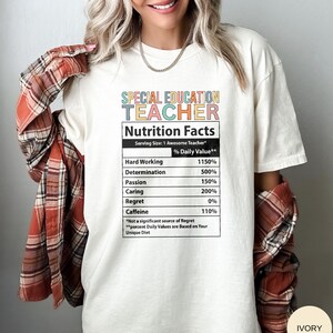 Op de afbeelding: Wit T-shirt met een kleurrijke afbeelding met de tekst "Special Education Teacher" en een voedingsschema met percentages voor hard werken, vastberadenheid, passie, zorg, spijt en cafe&iuml;ne. De tekst onderaan het schema luidt "*Geen significante bron van spijt **Procentuele dagelijkse waarden zijn gebaseerd op uw unieke dieet"