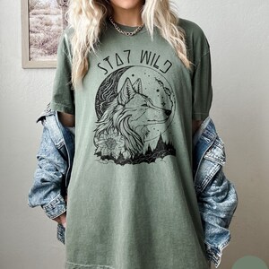 May include: A green t-shirt with a wolf howling at the moon graphic and the text "Stay Wild".