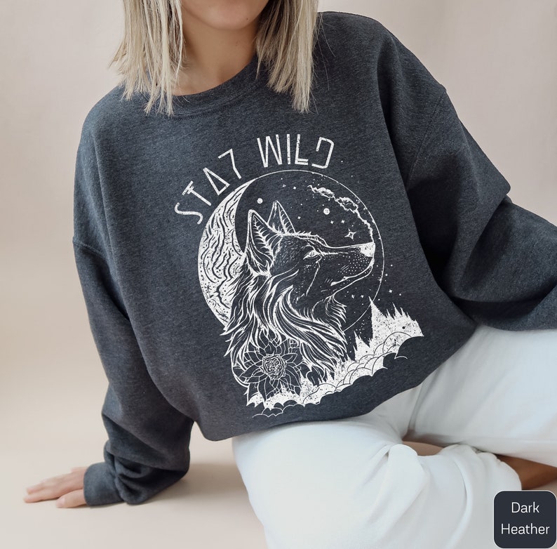 May include: Dark heather grey sweatshirt with a white wolf howling at the moon graphic and the text "Stay Wild".