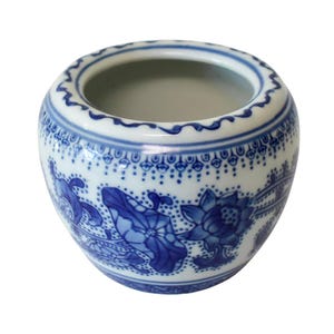May include: A small, round, white ceramic bowl with a blue floral design. The bowl features a scalloped rim and a detailed pattern of blue flowers and leaves. The interior is a plain, light gray color.