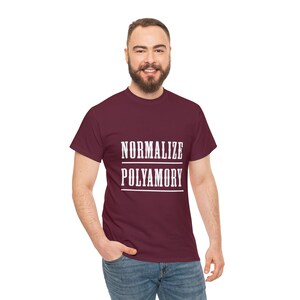 May include: A maroon t-shirt with the text "NORMALIZE POLYAMORY" printed in white.