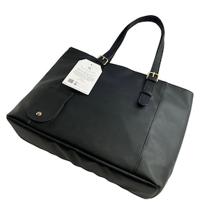 Peut inclure: Sac cabas noir avec une boucle dor&eacute;e et une petite poche sur le devant. Le sac a une &eacute;tiquette attach&eacute;e qui dit "Merci !"