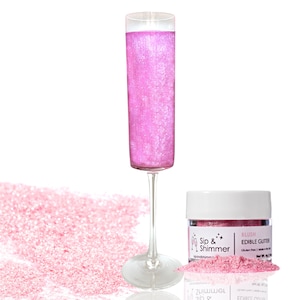 May include: A small jar of pink edible glitter labeled "Sip & Shimmer Blush Edible Glitter". The glitter is shown in a champagne flute and scattered on a white surface.