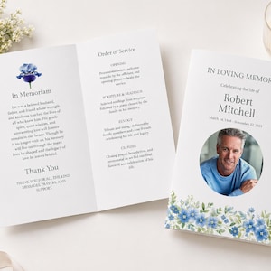 Könnte beinhalten: Ein weißes Programmheft für eine Trauerfeier mit einer blauen Iris-Illustration, dem Text In Loving Memory, Robert Mitchell, 14. März 1948 - 22. November 2023, einem kreisförmigen Foto eines Mannes und einem Order of Service Textabschnitt.