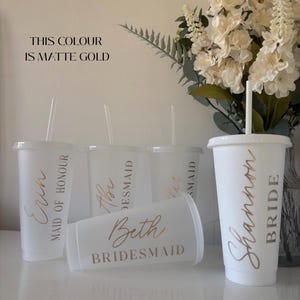 May include: Four frosted plastic tumblers with lids and straws, each featuring matte gold text. The cups are personalised with names and titles including Bride, Maid of Honour, and Bridesmaid. Text on the image states: THIS COLOUR IS MATTE GOLD.