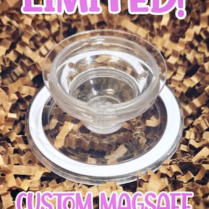 May include: Clear, circular PopSocket with a white rim, atop a brown, textured surface. The text "LIMITED!" and "CUSTOM MAGSAFE POPSOCKET" are displayed in pink. The PopSocket appears to be made of clear plastic.