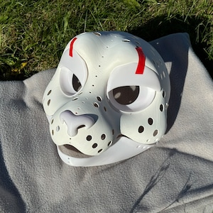 Op de afbeelding: Witte, onafgewerkte vachtdiermasker met rode markeringen rond de ogen. Het masker heeft een gedetailleerd neus- en mondgebied met gaten voor ventilatie.