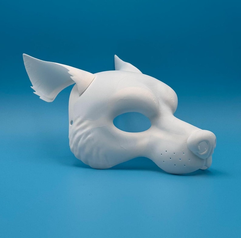May include: A white, unpainted, 3D printed animal mask with a wolf-like design. The mask has a large, open eye hole and a detailed snout with nostrils.