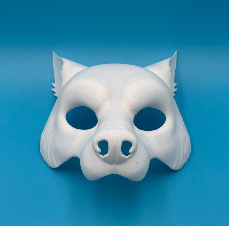 May include: A white wolf mask with a detailed snout and large eyes. The mask is made of a smooth, plastic-like material.
