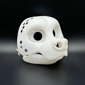 Könnte beinhalten: Weiße, unbemalte Felltiermaske mit Löchern für Augen und Nase. Die Maske besteht aus glattem, hartem Kunststoff.