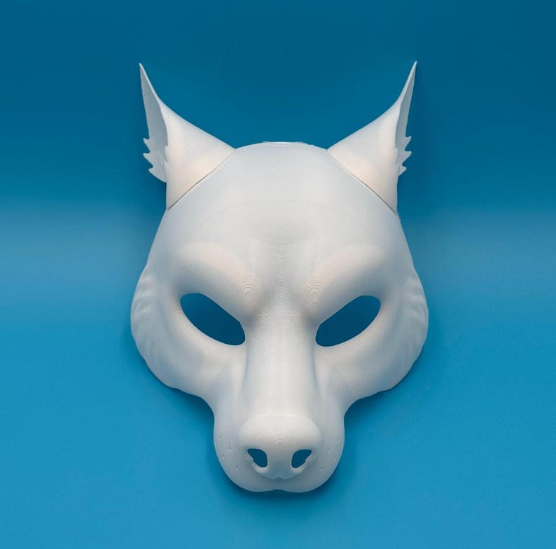 May include: White wolf mask with pointed ears and a detailed snout. The mask has eye holes and is made of a smooth, white material.
