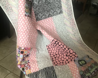 Pink prints and black swirls are on this crib size quilt/wall hanging/shower gift/or throw