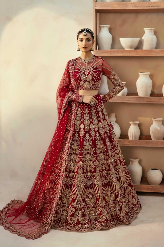 pakistani bride red dress Gold & Red Bridal Dress Pakistani in Lehenga Gown Style is an epitome of  tradition and royalty to have a magnificent appearance at the wedding.  Hand-crafted embellishments and golden work on this