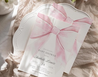May include: A pink watercolor bow with a white background. The text on the card reads "Please join us for a Baby Shower honoring Anabelle Louise August 24 2:00 PM Floral Garden 176 Berry Street, Santa Monica, CA RSVP to Katie at 802.543.4456 Registered at Target & Amazon"