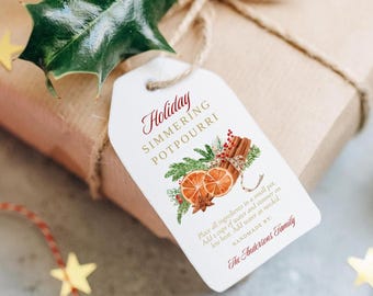 May include: A white gift tag with a red and gold design. The tag says "Holiday Simmering Potpourri" and includes instructions for making the potpourri. The tag is tied with twine to a brown gift box.