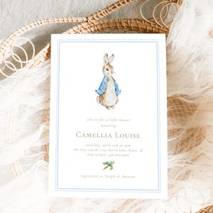 Pode incluir: Um convite para um chá de bebê com uma ilustração em aquarela do Peter Rabbit vestindo um casaco azul. O convite é para um chá de bebê em homenagem a Camellia Louise. O texto do convite diz "Junte-se a nós para um chá de bebê em homenagem a Camellia Louise, sábado, 2 de abril às 14h, The Rosy Ranch 123 Cherry Lane, Boise, ID. RSVP para Kate 216.007.0000. Registrado em Target & Amazon."