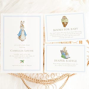 Può includere: Tre biglietti per la festa di nascita con un design blu e bianco. I biglietti presentano illustrazioni di Peter Rabbit. Un biglietto dice "Libri per il bambino" e chiede agli ospiti di portare un libro invece di un biglietto. Un altro biglietto dice "Lotteria dei pannolini" e chiede agli ospiti di portare un pacchetto di pannolini. Il terzo biglietto è un invito a una festa di nascita per Camellia Louise.