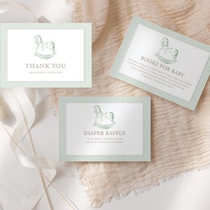 Puede incluir: Tres tarjetas de baby shower con una ilustración de caballito balancín. Las tarjetas incluyen los textos "Gracias", "Libros para bebé" y "Rifa de pañales". Las tarjetas tienen un borde a rayas verde claro y están sobre una tela de tono neutro.