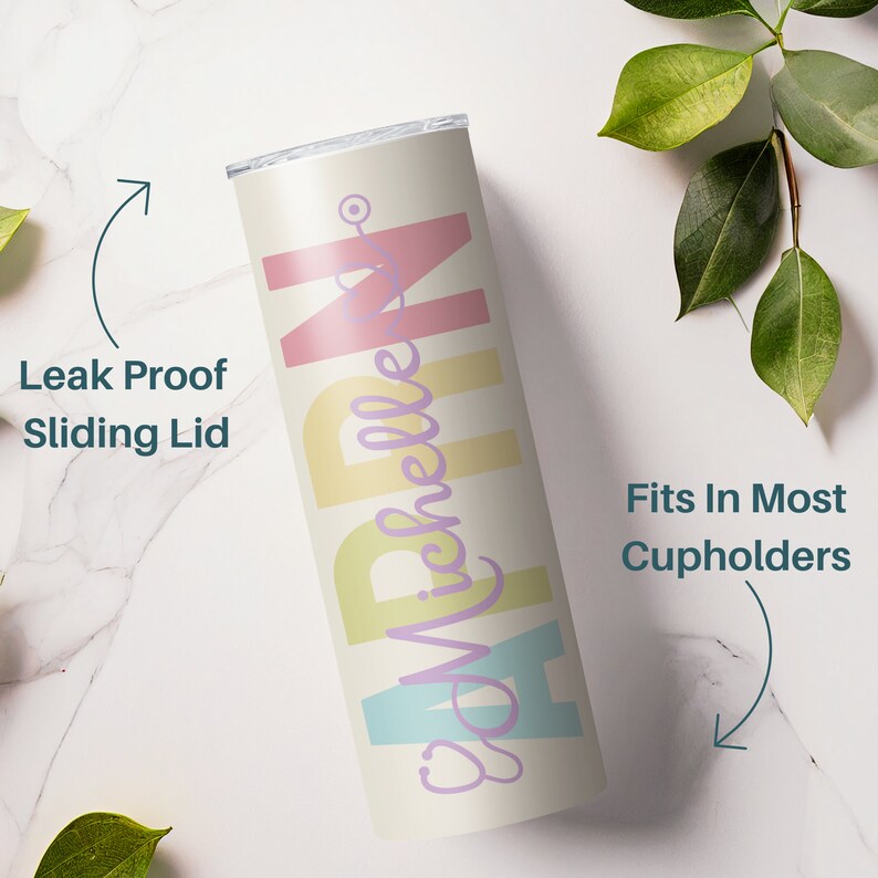 May include: A white stainless steel tumbler with a pastel rainbow design and the text "RN Michelle" in purple. The tumbler has a sliding lid and fits in most cupholders.