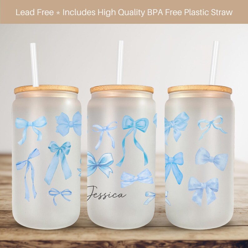 May include: Three frosted glass tumblers with bamboo lids and blue watercolor bow designs. The middle tumbler has the name "Jessica" written on it. Each tumbler comes with a clear plastic straw.