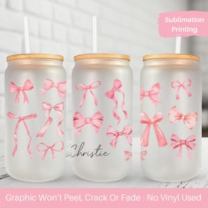 May include: Three frosted glass tumblers with bamboo lids and pink watercolor bow designs. The middle tumbler has the name "Christie" written on it. The text "Sublimation Printing" is in the top right corner of the image. The text "Graphic Won't Peel, Crack Or Fade - No Vinyl Used" is at the bottom of the image.