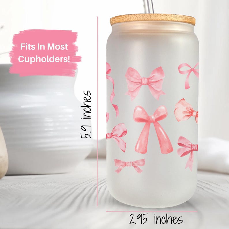May include: A frosted glass tumbler with a bamboo lid and a pink bow design. The tumbler is 5.9 inches tall and 2.95 inches wide. It says "Fits In Most Cupholders!"