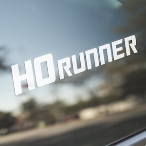 Könnte beinhalten: Weißer Vinyl-Aufkleber mit dem Text "4Runner" auf einem Autofenster.