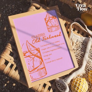 K&ouml;nnte beinhalten: Ein gerahmter Druck mit rosa Hintergrund und orangefarbenem Text und Illustrationen. Der Text lautet "CLASSIC Old Fashioned" mit einem Rezept f&uuml;r den Cocktail. Der Rahmen ist hellbraun.