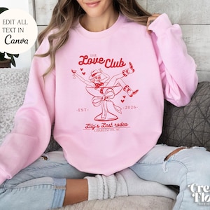 May include: Pink sweatshirt with a red graphic design of a woman in a cowboy hat sitting in a champagne glass. The text reads "The Love Club -EST- 2026- Lily's Last Rodeo CHARLESTON, SC"