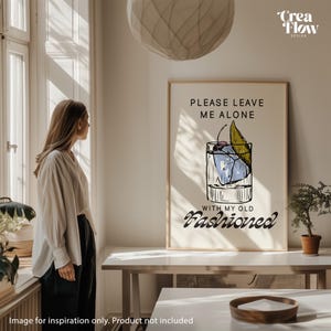 K&ouml;nnte beinhalten: Ein gerahmter Druck mit dem Text "PLEASE LEAVE ME ALONE WITH MY OLD FASHIONED" und einer Cocktail-Illustration. Das Kunstwerk hat einen beigen Hintergrund und ein minimalistisches Design, geeignet f&uuml;r die Inneneinrichtung.