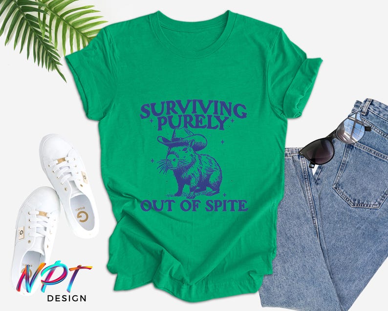 May include: Green t-shirt with a blue graphic of a capybara wearing a witch hat and the text "Surviving Purely Out of Spite".