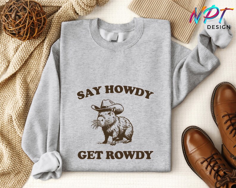 May include: A gray sweatshirt with the text "Say Howdy Get Rowdy" and a cartoon capybara wearing a cowboy hat.