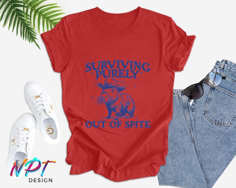 May include: Red t-shirt with a blue graphic of a cartoon animal wearing a sombrero and the text "Surviving Purely Out of Spite".