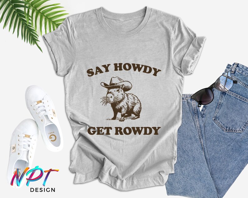 May include: A gray t-shirt with the text "Say Howdy Get Rowdy" and a cartoon image of a capybara wearing a cowboy hat.