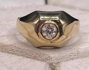 May include: A gold ring with a single round diamond set in the center. The ring has a textured, slightly domed design.