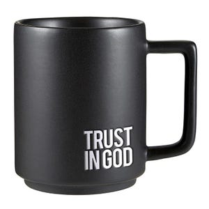May include: A black ceramic mug with a square handle. The mug features the white text "TRUST IN GOD" on the side. The mug has a matte finish and a simple, modern design.